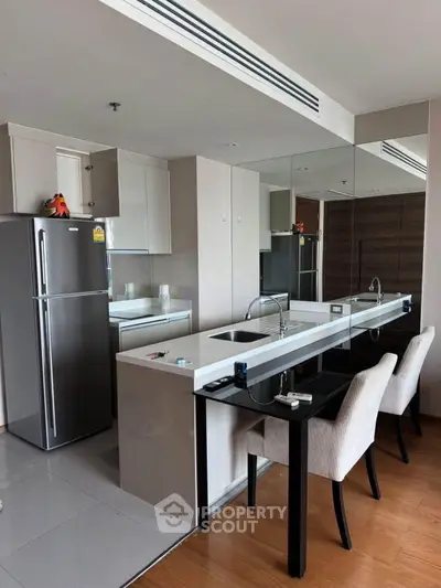 Modern kitchen with sleek design, featuring a breakfast bar and stainless steel appliances in a stylish apartment.