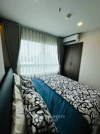 Cozy bedroom with modern decor and large window offering natural light.