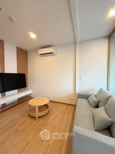 Modern living room with sleek design, featuring a comfortable sofa, wall-mounted TV, and stylish wooden accents.