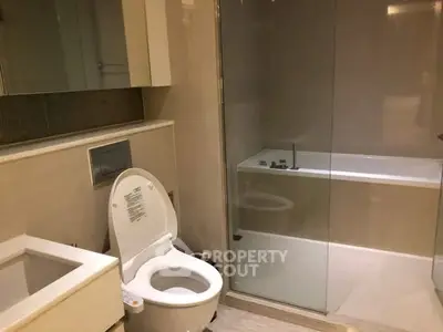 Modern bathroom with sleek fixtures and glass-enclosed bathtub
