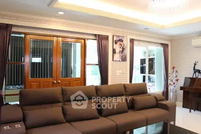 Spacious living room with elegant decor and plush sofa, featuring large windows and stylish lighting.
