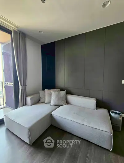 Modern living room with sleek gray sofa and large windows offering natural light.