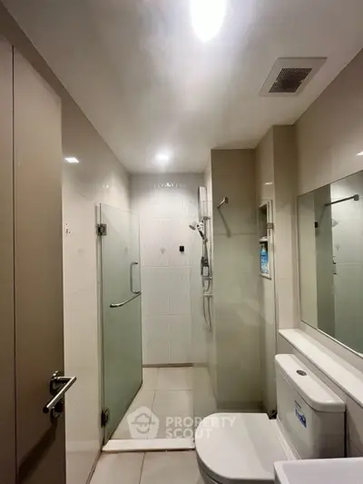 Modern bathroom with glass shower and sleek fixtures in contemporary apartment.