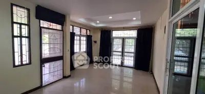 Spacious living room with large windows and elegant curtains, perfect for natural light and comfort.