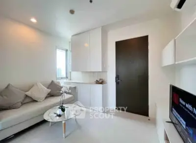 Modern living room with cozy sofa, sleek cabinetry, and wall-mounted TV in a bright apartment.