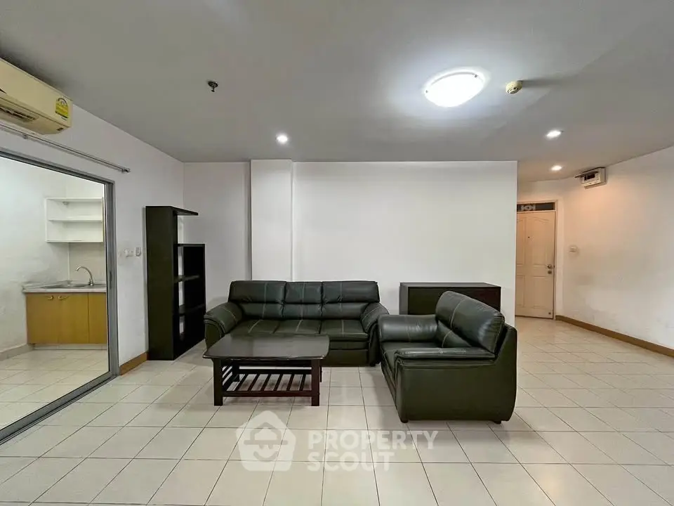 Spacious living room with modern leather sofa and open kitchen layout