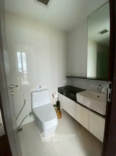 Modern bathroom with sleek fixtures and large mirror in a contemporary home.