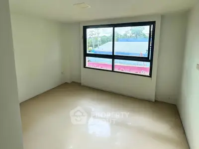 Spacious empty room with large window and natural light, ideal for customization.