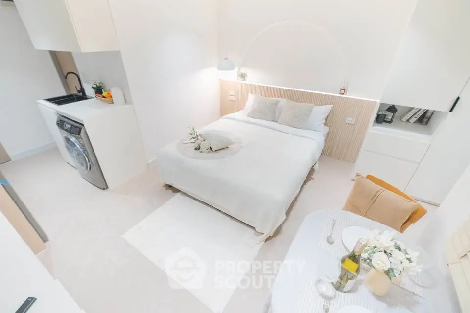 Chic studio apartment with modern decor, cozy bed, and compact kitchen area, perfect for urban living.