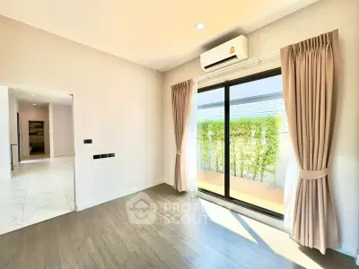 Bright living room with large sliding doors leading to a private balcony, featuring elegant curtains and modern flooring.