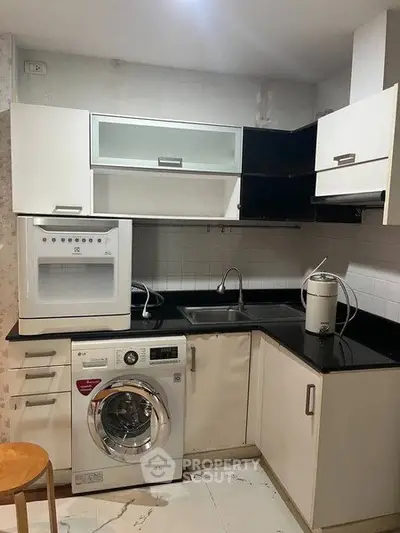 Modern kitchen with sleek cabinetry, washing machine, and microwave, perfect for urban living.