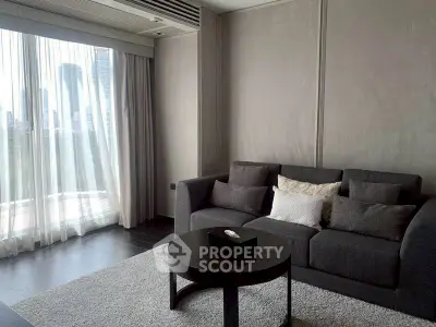 Modern living room with city view, featuring sleek gray sofa and elegant decor.