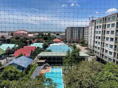 Stunning aerial view of residential buildings with lush greenery and a sparkling pool under a clear blue sky.