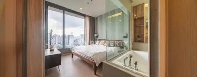 Luxurious bedroom with stunning city view and modern bathtub in high-rise apartment.