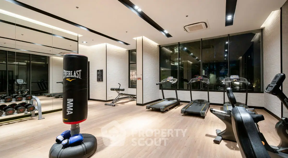 Modern gym with treadmills, punching bag, and weights in luxury apartment complex.