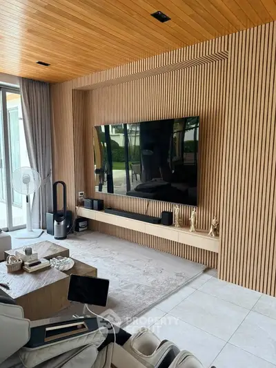 Modern living room with wooden paneling, large TV, and stylish decor in a luxury home.