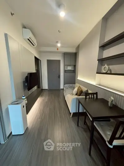 Modern living room with sleek design, featuring a cozy sofa, dining table, and wall-mounted TV.