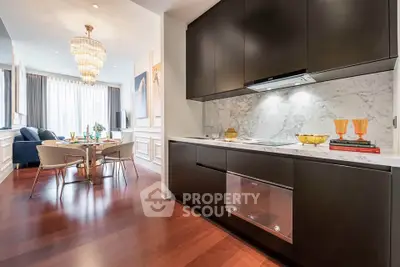 Luxurious open layout kitchen and dining area with elegant chandelier and hardwood floors.