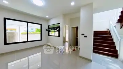 Spacious modern living room with large windows and sleek staircase