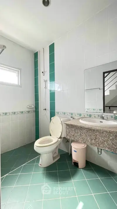 Bright and spacious bathroom with modern fixtures and green tile accents.