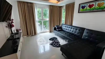 Spacious modern living room with large windows and stylish black furniture.