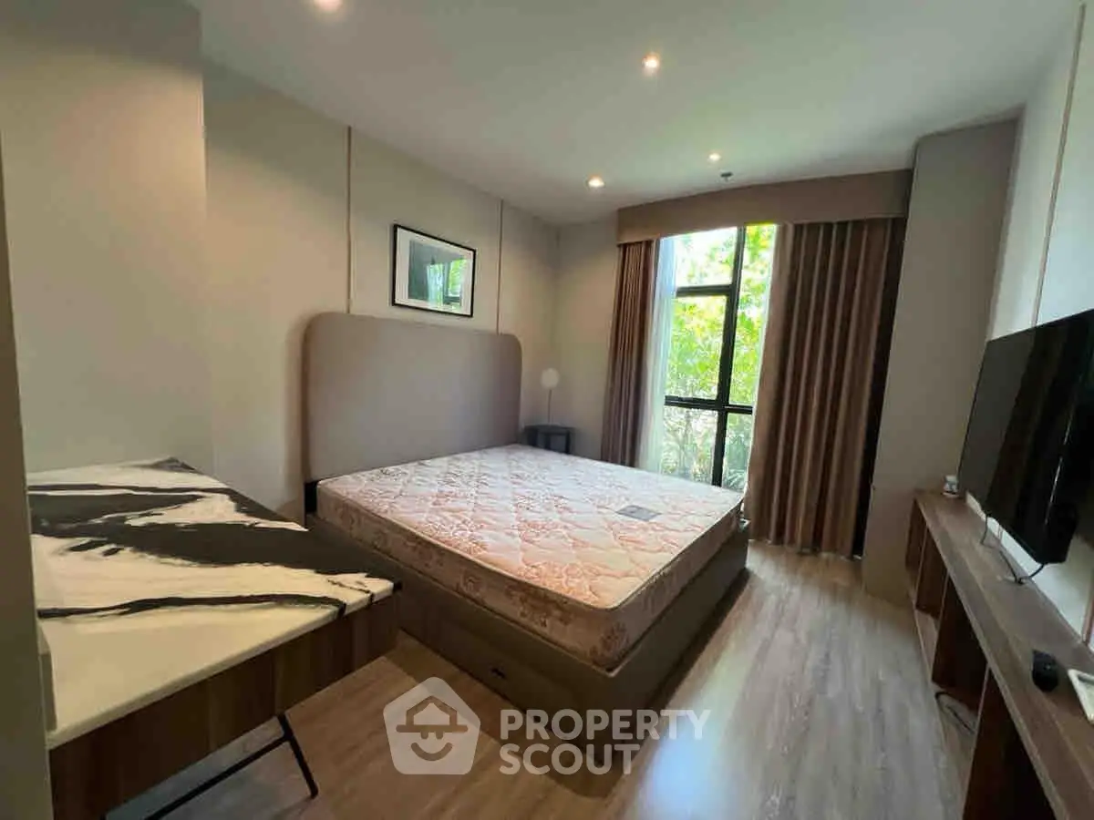 Modern bedroom with large window and stylish decor in a contemporary apartment.