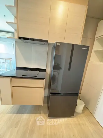 Modern kitchen with sleek fridge and induction cooktop in stylish apartment.