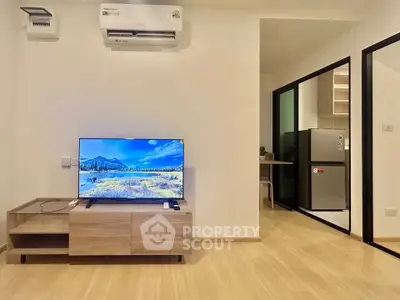 Modern living room with sleek TV setup and view into stylish kitchen