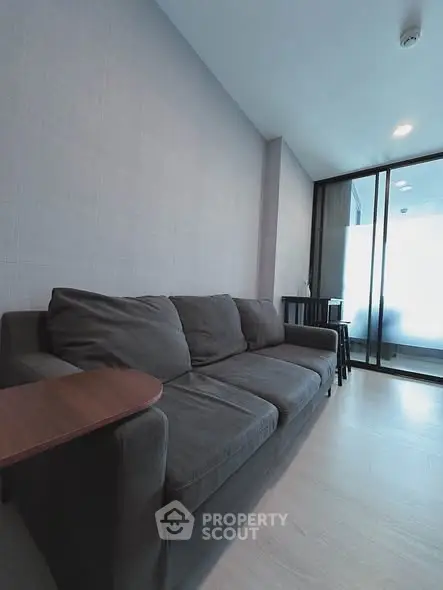 Modern living room with sleek gray sofa and glass partition, perfect for urban living.