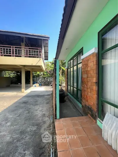 Charming exterior view of a vibrant green house with spacious driveway and brick accents.