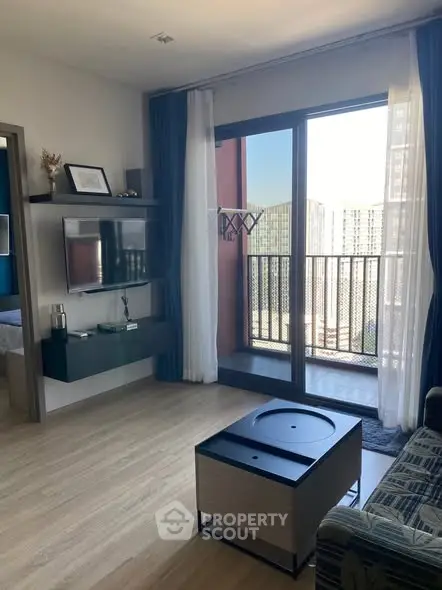 Modern living room with balcony and city view, featuring sleek furniture and natural light.