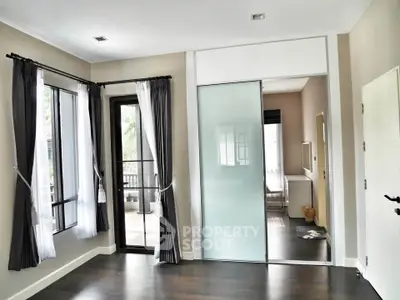 Spacious modern living room with large windows and sliding glass door leading to a balcony.
