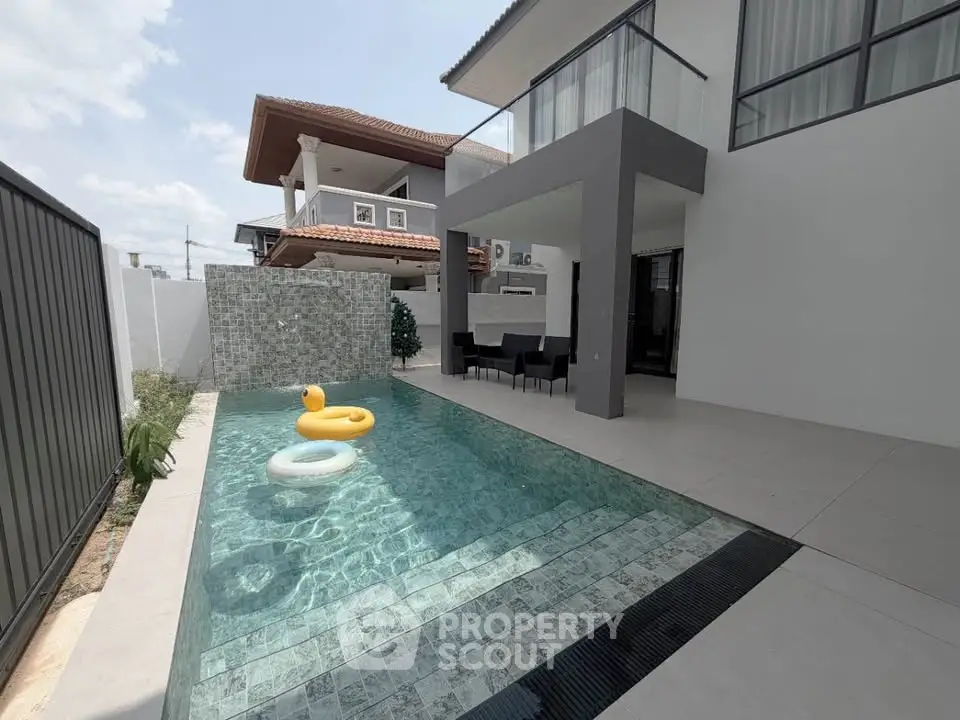 Modern home with sleek pool and stylish outdoor seating area, perfect for relaxation and entertainment.