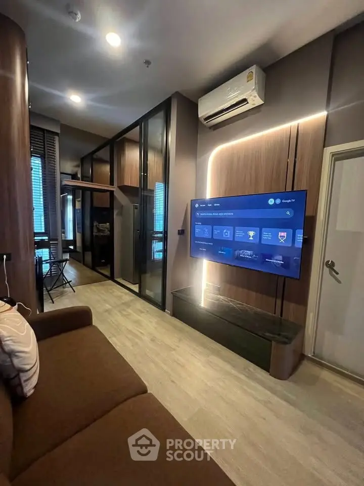 Modern living room with sleek design, featuring a wall-mounted TV and stylish lighting.
