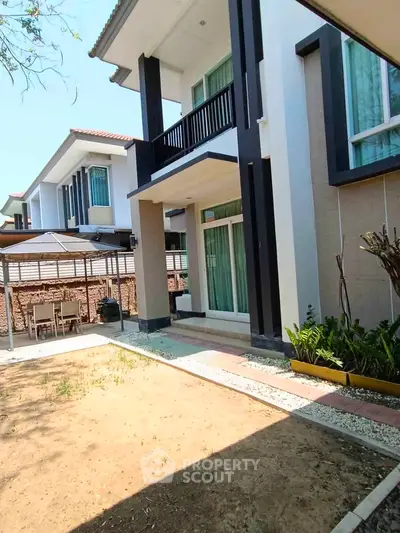 Modern two-story house with balcony and spacious garden area