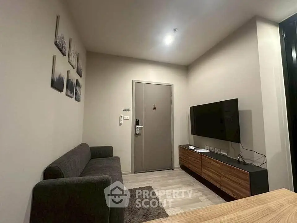 Modern living room with sleek furniture and wall-mounted TV in a cozy apartment.