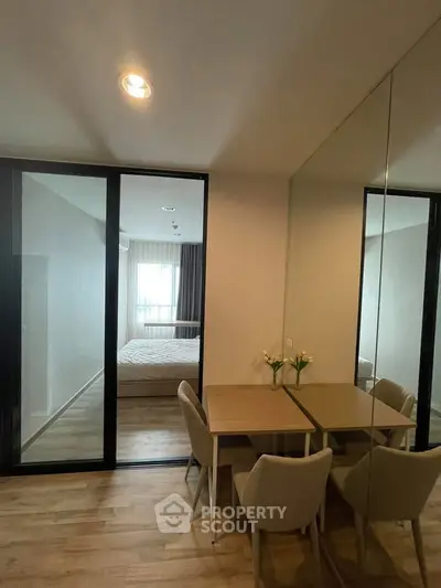 Modern apartment interior with dining area and bedroom view, featuring sleek design and cozy ambiance.