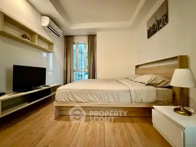 Modern bedroom with wooden flooring, stylish bed, and wall-mounted TV in a cozy apartment.
