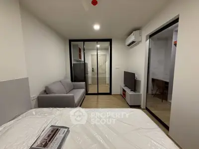Modern bedroom with glass partition, cozy sofa, and wall-mounted TV in a stylish apartment.