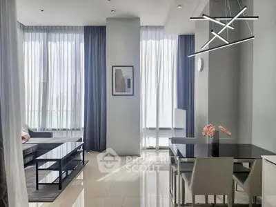 Modern living and dining area with sleek furniture and large windows in a stylish apartment.