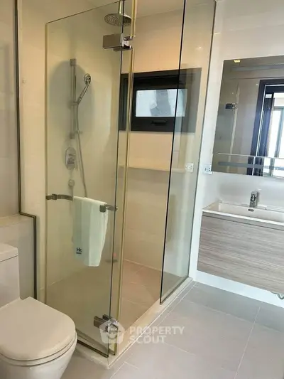 Modern bathroom with glass shower enclosure and sleek vanity in a contemporary home.