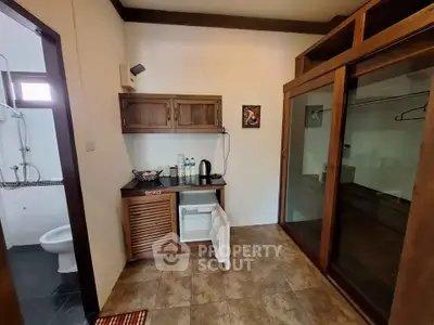 Charming interior with wooden cabinets and glass sliding doors, featuring a compact kitchenette and bathroom access.