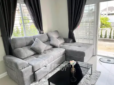 Stylish living room with plush gray sectional sofa and elegant decor, featuring large windows and balcony access.