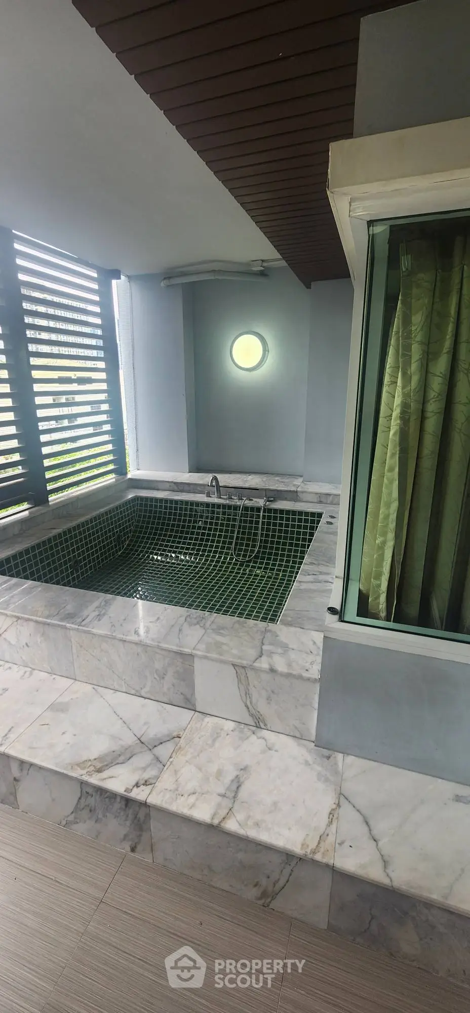 Luxurious marble-tiled outdoor jacuzzi with privacy screen and modern lighting.