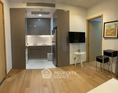 Modern apartment interior with open kitchen and stylish living area, featuring wooden flooring and sleek cabinetry.