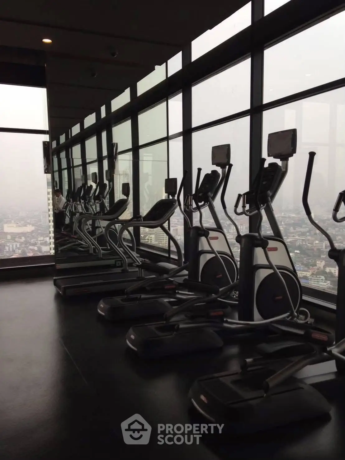 High-rise gym with panoramic city views and modern exercise equipment.