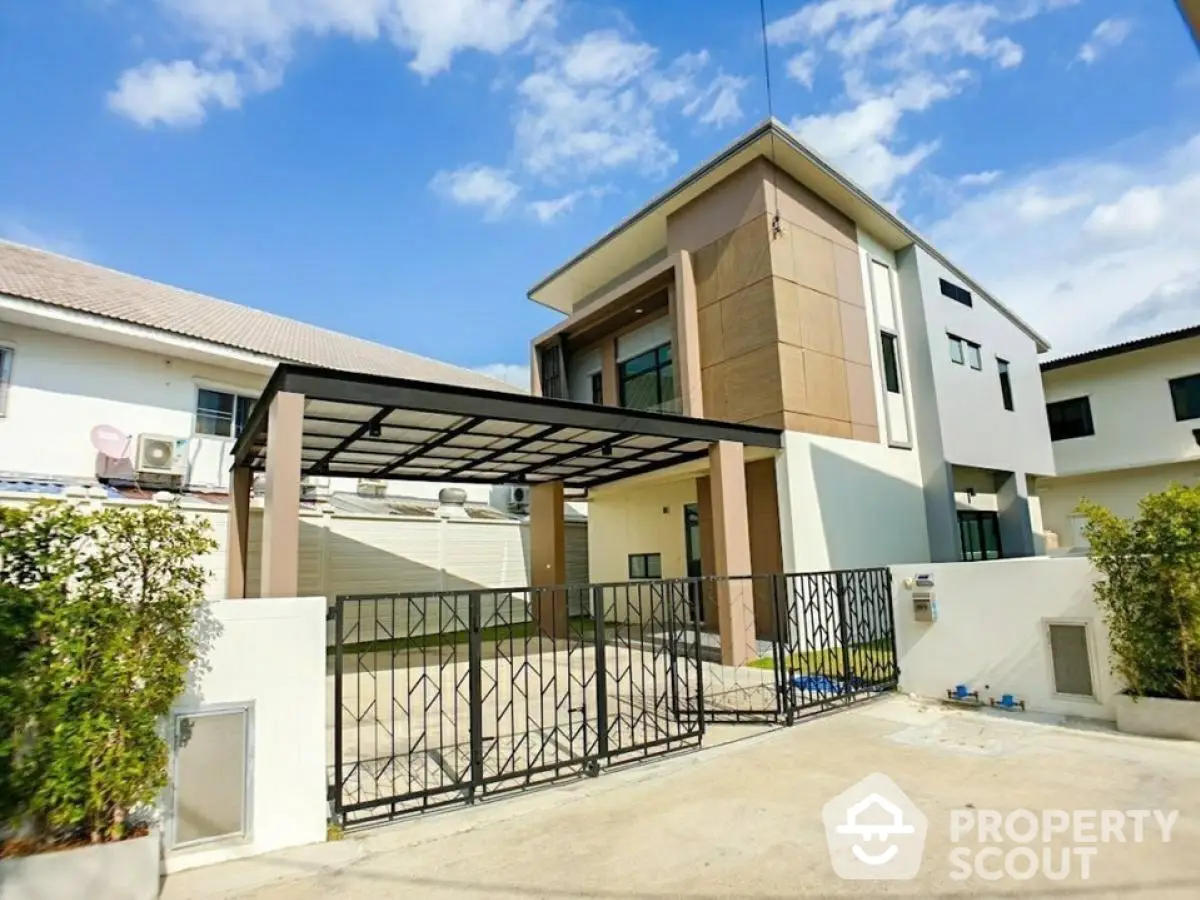 Modern two-story house with gated entrance and carport in a suburban neighborhood.