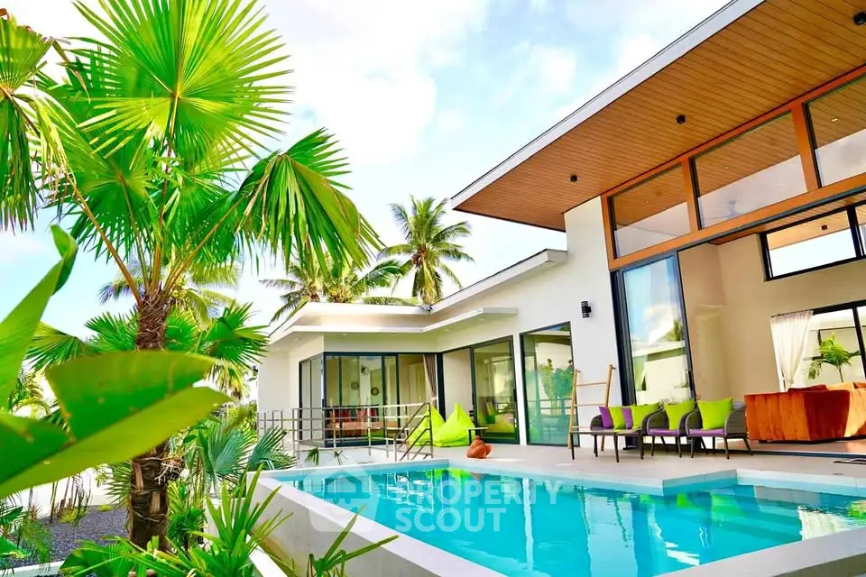 Luxurious modern villa with pool and tropical garden, featuring expansive glass windows and stylish architecture.