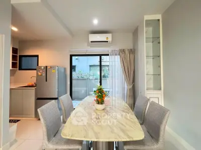 Modern dining area with marble table, stylish chairs, and sleek kitchen in open layout.