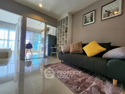 Modern living room with stylish decor and open view to bedroom, featuring plush sofa and sleek flooring.